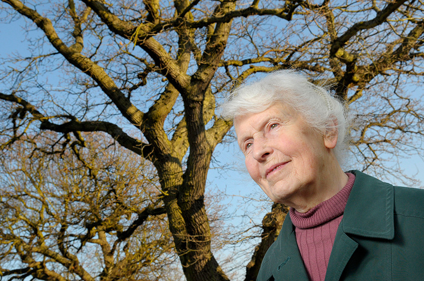 Jean Combes OBE smiling next to trees